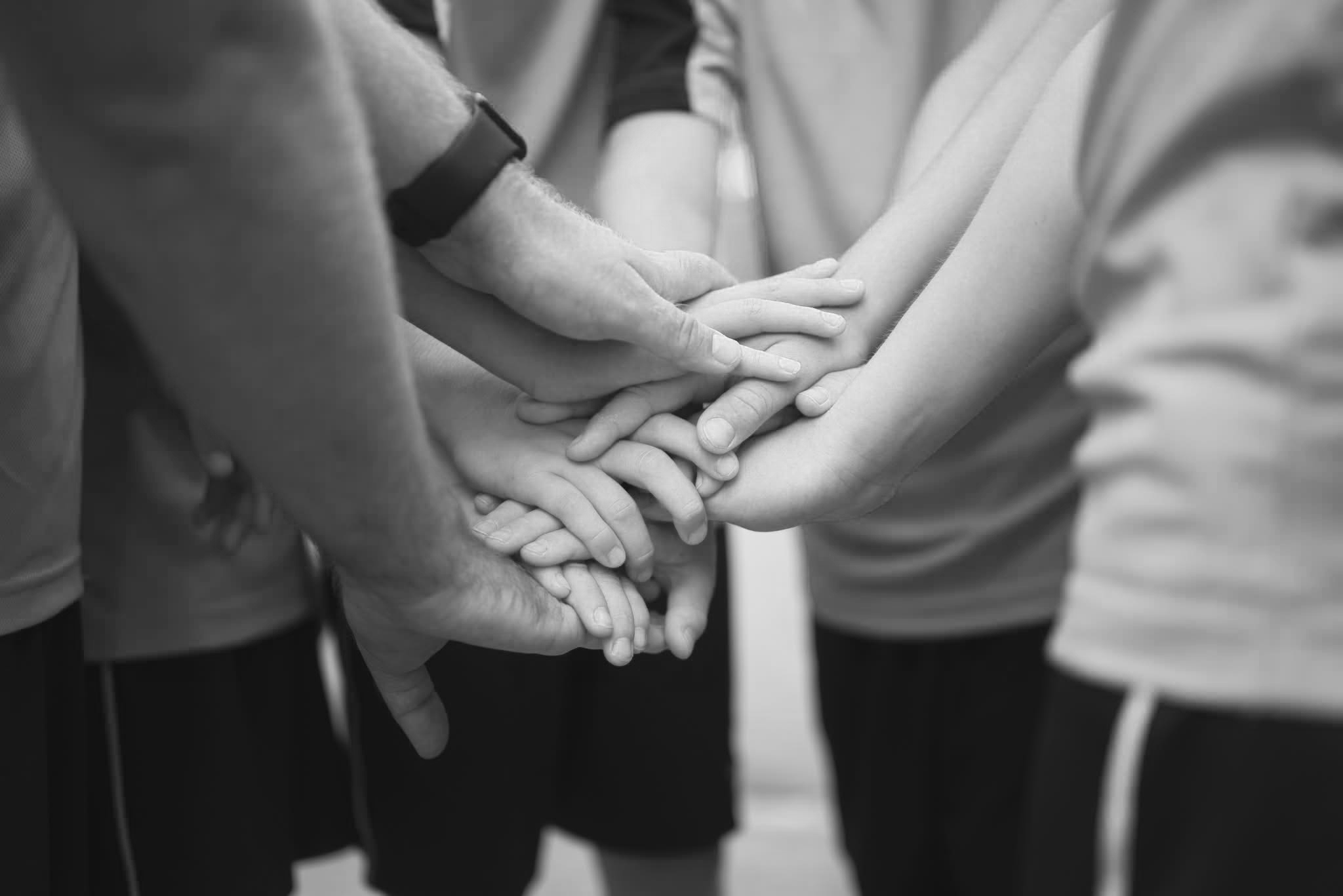 Mehrere Personen legen ihre Hände zusammen und symbolisieren Zusammenarbeit